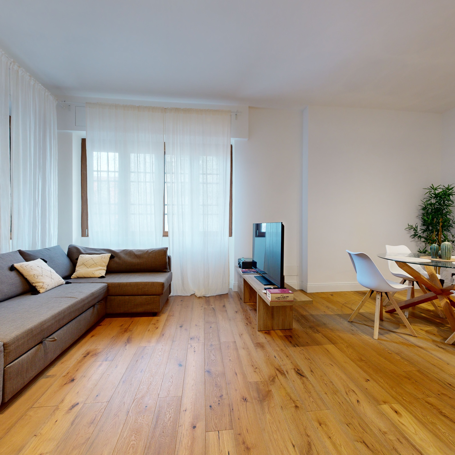 Soggiorno luminoso con parquet e divano, Casa Ricciarelli Milano Buonarroti